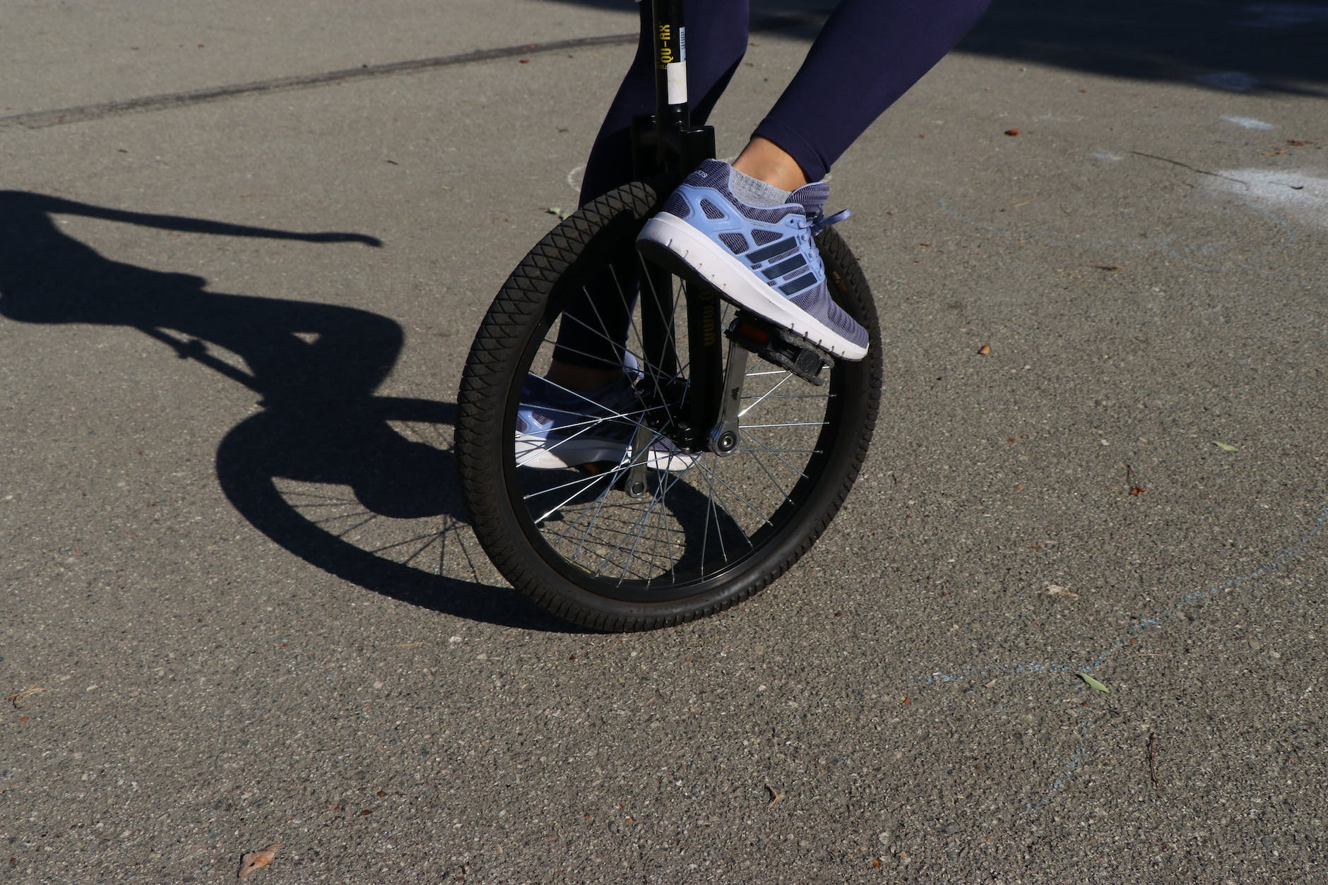 crop person riding unicycle on asphalt road