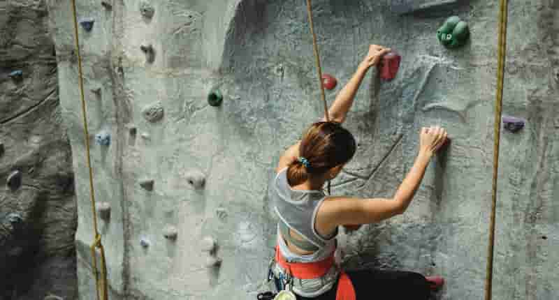 strong female alpinist climbing in gym