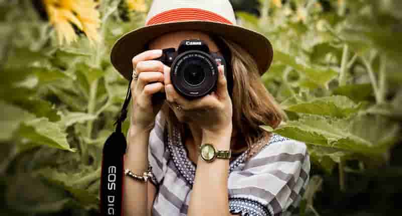 selective focus photography of woman holding dslr camera