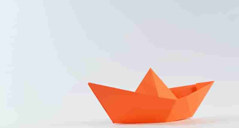 orange paper boat on white surface