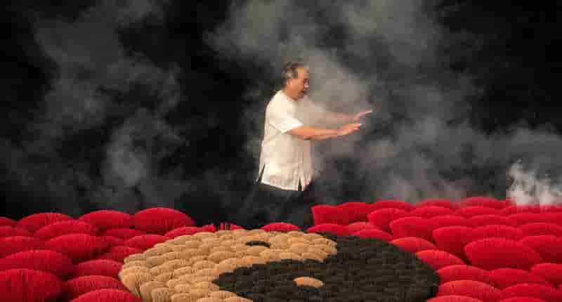 man practicing tai chi next to incenses forming ying yang symbol