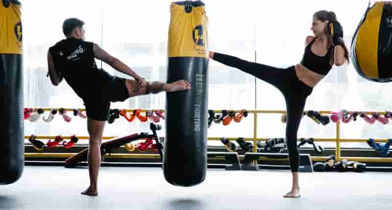 fit man and woman practicing kickboxing in gym