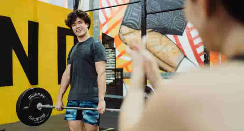 smiling athlete lifting barbell in gym