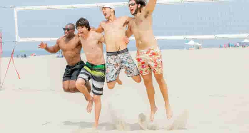 men jumping on a beach volleyball court