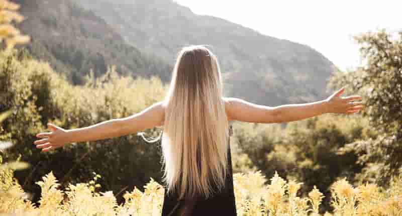 standing woman in black dress facing mountain