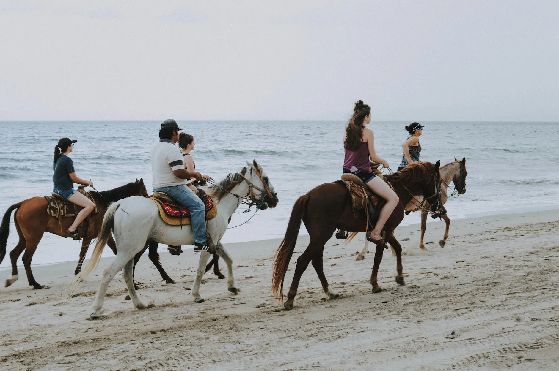 people riding horses on beach