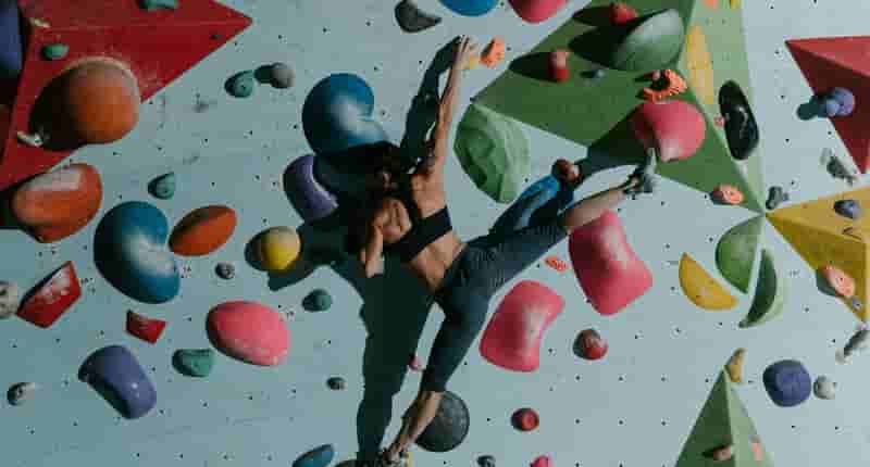 A Woman Climbing a Bouldering Wall