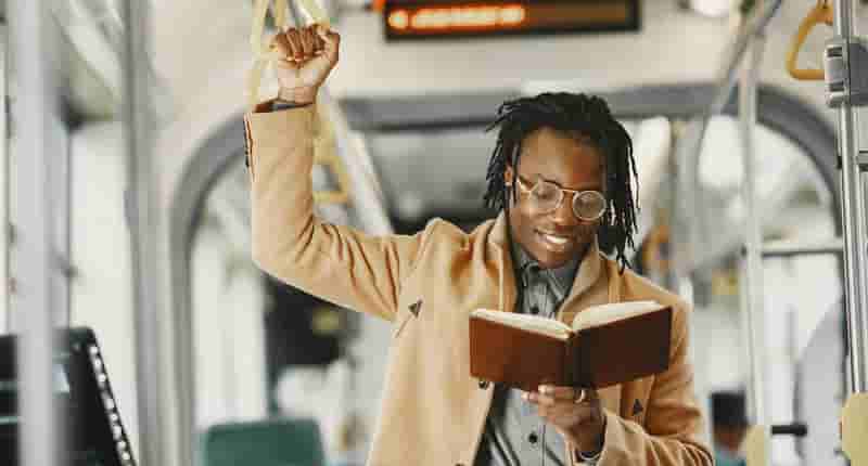 Young Man Reading a Book in a Bus