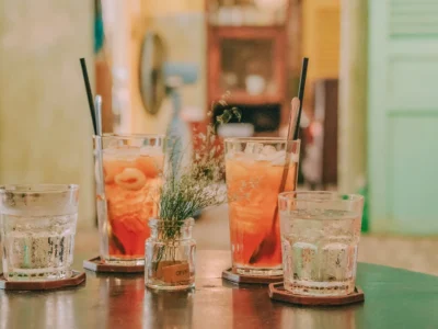 four clear glass drinking cups filled with orange and clear liquids on black surface