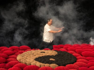 man practicing tai chi next to incenses forming ying yang symbol