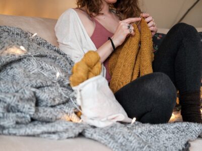 woman sitting on a sofa while knitting a sweater