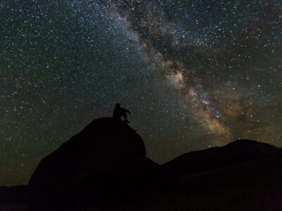 silhouette of person sitting on rock
