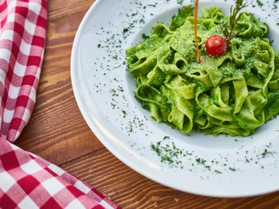 flat pasta noodle with green sauce dish and cherry tomato on top