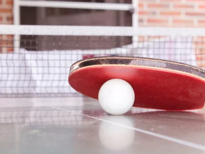 white pingpong ball beneath red table tennis paddle
