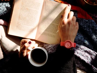 person reading book and holding coffee