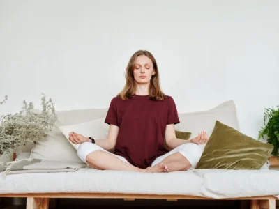 woman in red shirt sitting on couch meditating