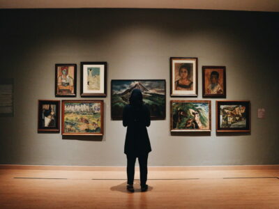woman in black coat standing in front of paintings