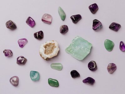 Flat lay of assorted polished gemstones including amethyst and jade on a light background.