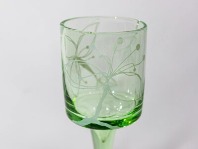 A stylish green glass with intricate design on a plain background, ideal for decoration.